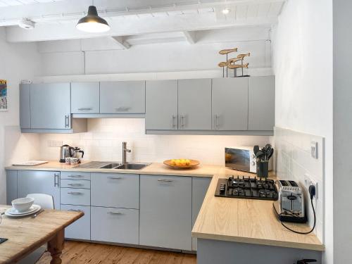 a kitchen with white cabinets and a wooden counter top at Nautilus in St Ives