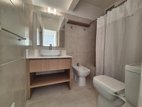 een badkamer met een wastafel, een toilet en een spiegel bij Apart Edificio Vanguardia frente al mar in Punta del Este