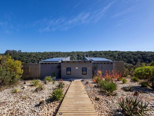 a house with a wooden walkway in front of it at Cliffside Suites in Plettenberg Bay