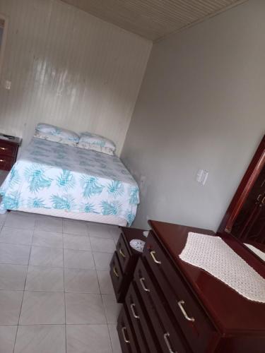 a small bedroom with a bed and a dresser at Casa Azul da Marina in Três Coroas