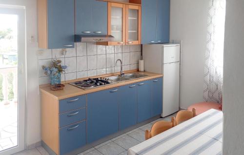 cocina con armarios azules, fregadero y nevera en Amazing Apartment In Lopar With Wifi, en Lopar
