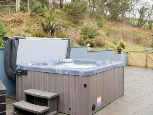 a hot tub sitting on a patio with two benches at Beudy-Oh2 in Dihewid