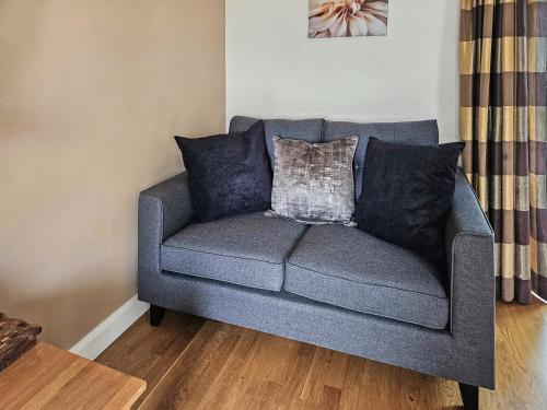 un sofá gris con almohadas en la sala de estar en Beudy-Oh2, en Dihewid