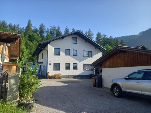 una gran casa blanca con un coche aparcado delante de ella en beim Anderl, en Oberammergau