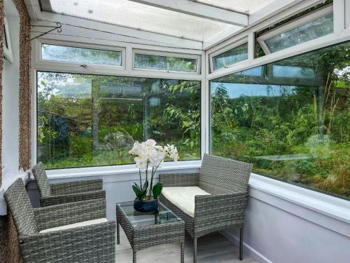 a screened in porch with chairs and a table with flowers at Acreknowe Cottage in Hawick