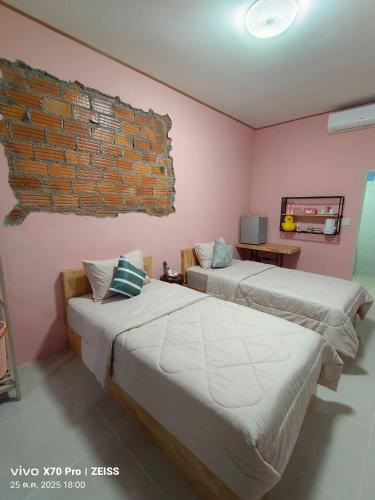 a bedroom with two beds and a brick wall at Da-Kanda Boutique in Klong Muang Beach