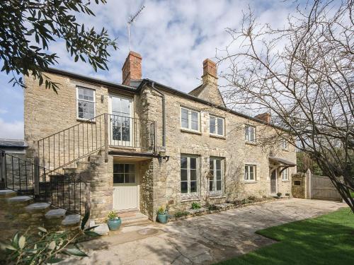 une grande maison en pierre avec un escalier en face de celle-ci dans l'établissement Holliers Cottage, à Ledwell