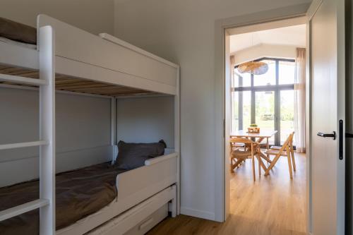 a bedroom with bunk beds and a dining room with a table at Nordic Zen 2BR Beach House - Bali-Inspired Calm in Skulte