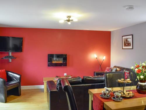 a living room with red walls and a couch and a table at Cartws-Oh3 in Dihewid