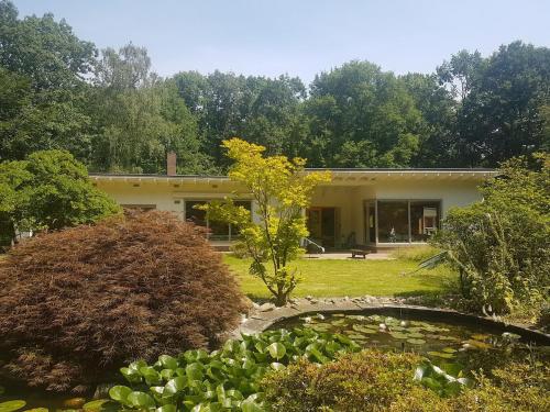 a house with a pond in front of it at Unique retro bungalow on the Veluwe in Wageningen