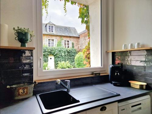 Una encimera de cocina con un fregadero y una ventana. en Le Secret - Cozy Normandy Home with garden, en Neufchâtel-en-Bray