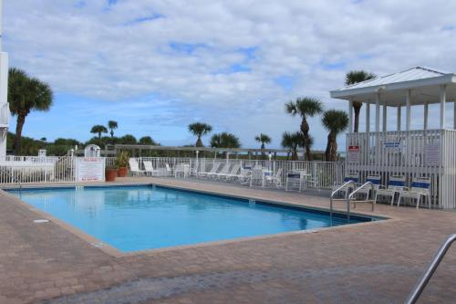 a swimming pool with chairs and a pavilion at Oceanfront 2br2b, Ocean Views, Heated Pool, Spa in Cape Canaveral