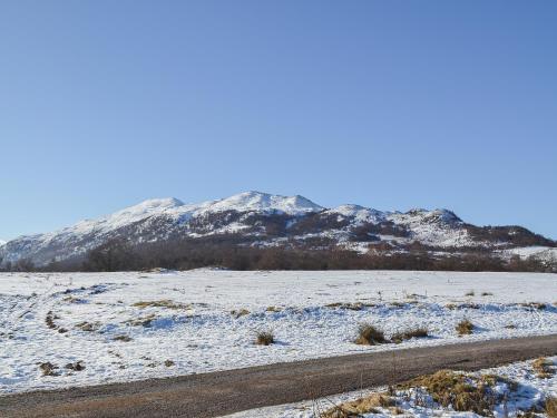 a snowy field with a mountain in the background at Bruich Cottage in Newtonmore