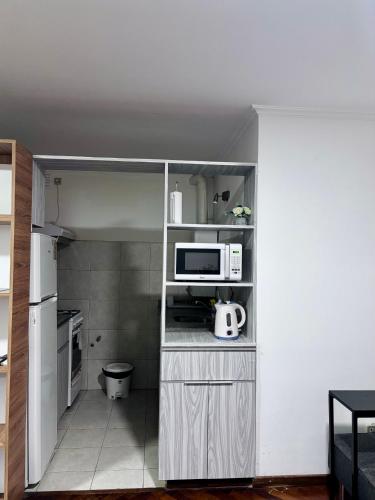 a small kitchen with a microwave and a refrigerator at Departamento Frente Campus UNC in Cordoba