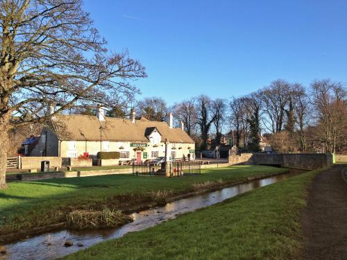 a house with a river in front of it at Jug And Glass Cottage in Upper Langwith