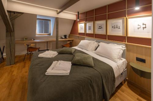 a bedroom with a large bed with two towels on it at Céhes Guesthouse in Târgu Secuiesc