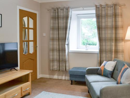 a living room with a couch and a window at Blackmill Cottages No 2 in Taynuilt