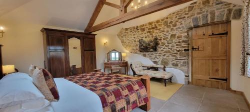 ein Schlafzimmer mit einem Bett und einer Steinwand in der Unterkunft 18th century renovated barn in beautiful Devon countryside in Broadwoodwidger