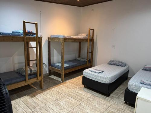 QUARTOS Praia do Tombo Guarujá في غوارويا: غرفة بها ثلاثة أسرة بطابقين وسرير