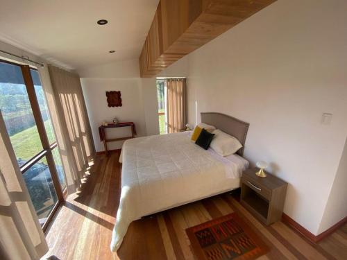 une chambre avec un lit et une grande fenêtre dans l'établissement Apus Paradise House Valle Sagrado, à Urubamba