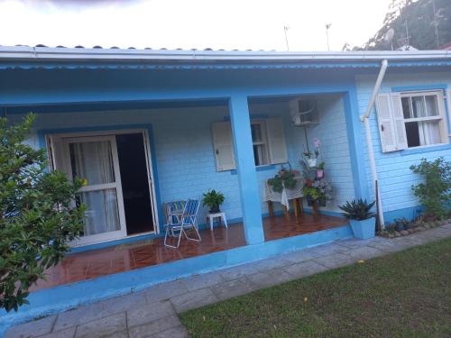 ein blaues Haus mit einer Veranda mit 2 Stühlen in der Unterkunft Casa da Marina in Três Coroas