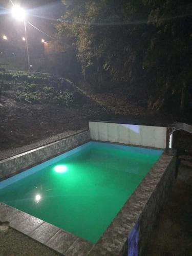 a swimming pool with green water at night at Pablo's place in Rezine