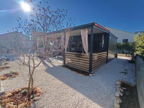 a small shed with a tree in a yard at Villa Isabell - Camp Limoni 12 in Sukošan