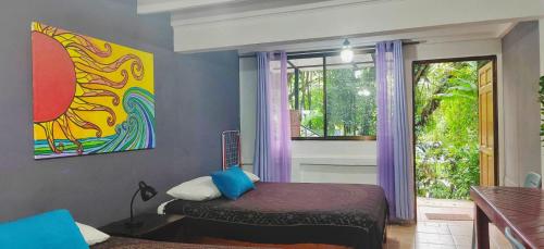 a bedroom with a bed and a painting on the wall at Jungle Beach Hotel Manuel Antonio in Manuel Antonio