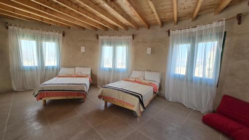 two beds sitting in a room with windows at Marcelia Eco-Village Front Lake View in Siwa