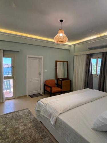a bedroom with a bed and a chair and windows at Golden Sun House II in Abu Simbel