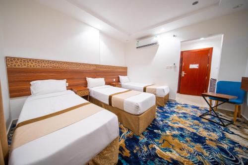 a hotel room with two beds and a desk at Saif Plus 1 Hotel by Orvana in Makkah