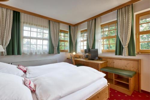 a bedroom with two beds and a desk with a television at Hotel Alpenhof - ruhige Wohlfühloase zwischen München, dem Fünf-Seenland und den Bergen, in S-Bahnnähe in Gauting
