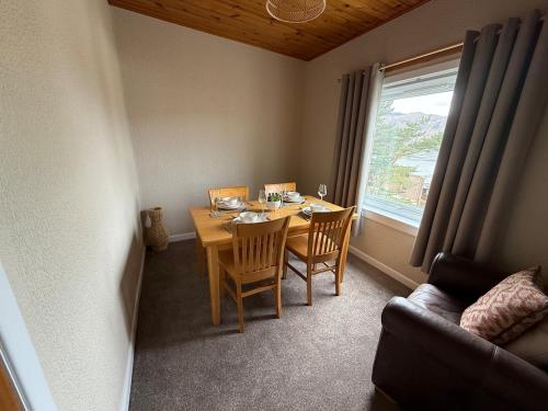 ein Esszimmer mit Tisch und Stühlen und einem Fenster in der Unterkunft Lesmar Highland Retreat in Fort William