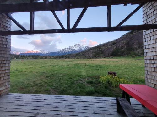 a view of mountains from a porch with a red bench at Refugio Cerro Castillo in Villa Cerro Castillo