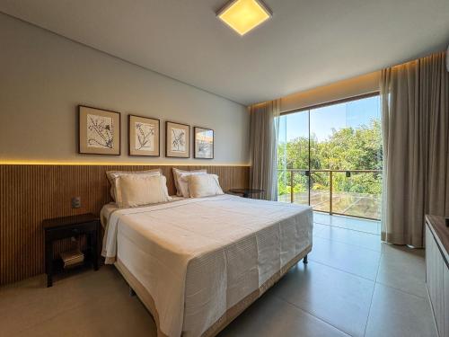 a bedroom with a large bed and a large window at Casa Kuará Praia do Forte in Praia do Forte
