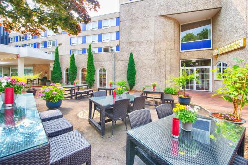 a patio with tables and chairs in front of a building at Leonardo Hotel Hamburg City Nord in Hamburg