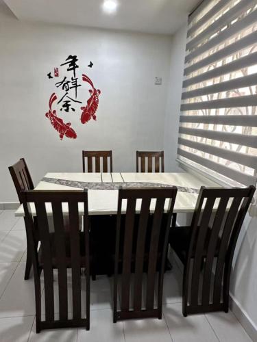 a dining room table with chairs and chinese writing on the wall at 家家民宿 in Nibung Tebal