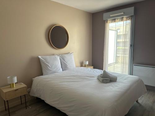 Schlafzimmer mit einem weißen Bett und einem Spiegel an der Wand in der Unterkunft Le Manet, Lagny-sur-Marne in Lagny