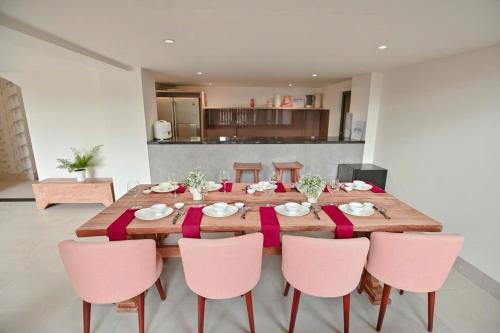 Kon Rung (1)Swan Suite Villa Đà Lạt的餐桌周围摆放着粉红色椅子