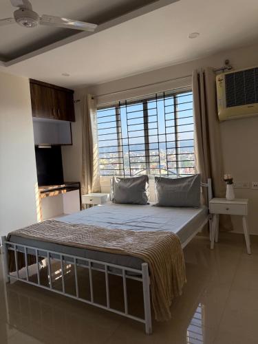 a bedroom with a large bed with a large window at Bela D Casa - 3BHK overlooking mountains and city in Guwahati