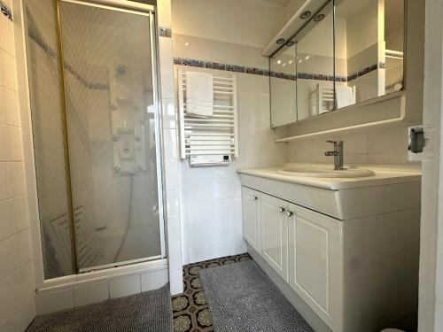 Un baño blanco con ducha y lavabo. en Le Magellan Coulommiers 77, en Coulommiers