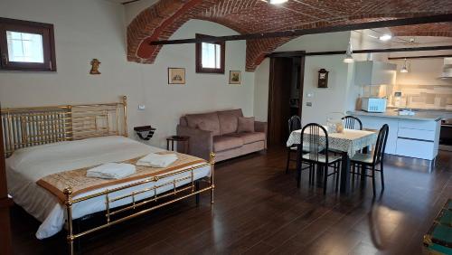 a bedroom with a bed and a table and a kitchen at Cascina Tetto Cavallo Monolocale Rustico in Revello