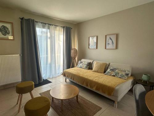 a living room with a couch in front of a window at Les Alois 10 min to Disneyland in Couilly-Pont-aux-Dames