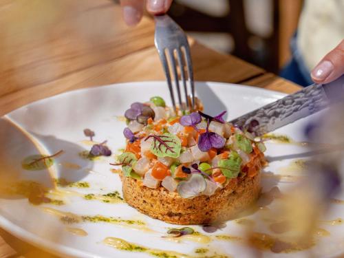 ムジェーヴにあるNovotel Megève Mont-Blancのフォークとナイフを使って食べ物を食べる人