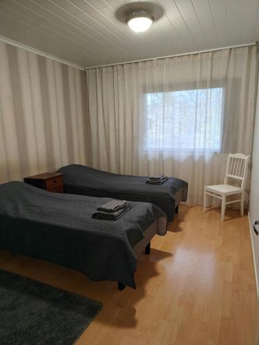 two beds in a room with a chair and a window at Kottaraispari in Imatra