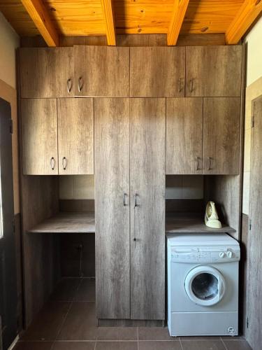 a laundry room with a washing machine and wooden cabinets at Wine Studio with BBQ & pool in Las Heras