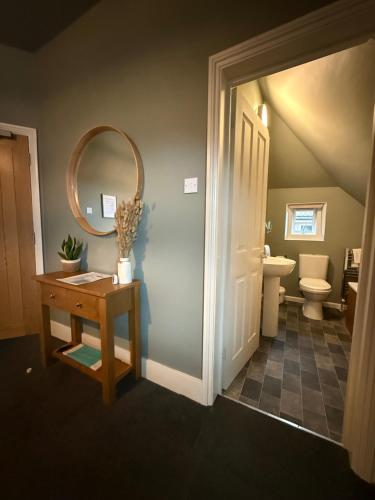 a bathroom with a toilet and a table with a mirror at The Albany Rooms Bexhill in Bexhill