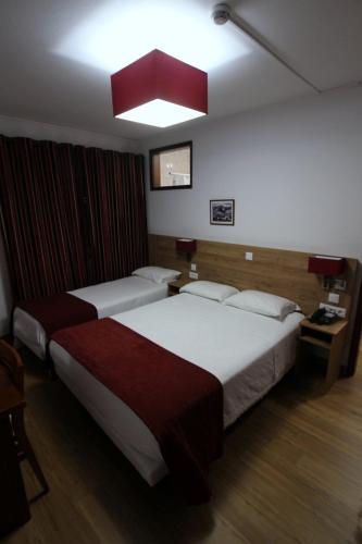 a hotel room with two beds and a light at Hotel Rota Malhoa in Figueiró dos Vinhos