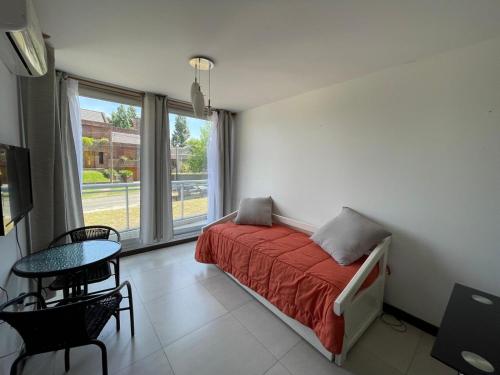 ein Schlafzimmer mit einem Bett und einem Tisch und einem Fenster in der Unterkunft Altos Del Plata 105 y 505 Colonia Uruguay in Colonia del Sacramento