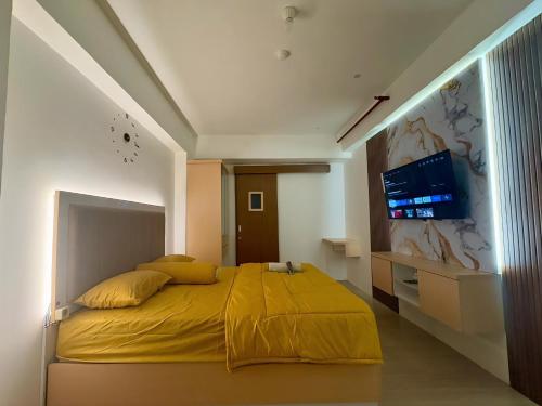 ein Schlafzimmer mit einem gelben Bett und einem TV an der Wand in der Unterkunft Apartemen Gunung Putri by Maknyoss Rooms in Pabuaran Satu